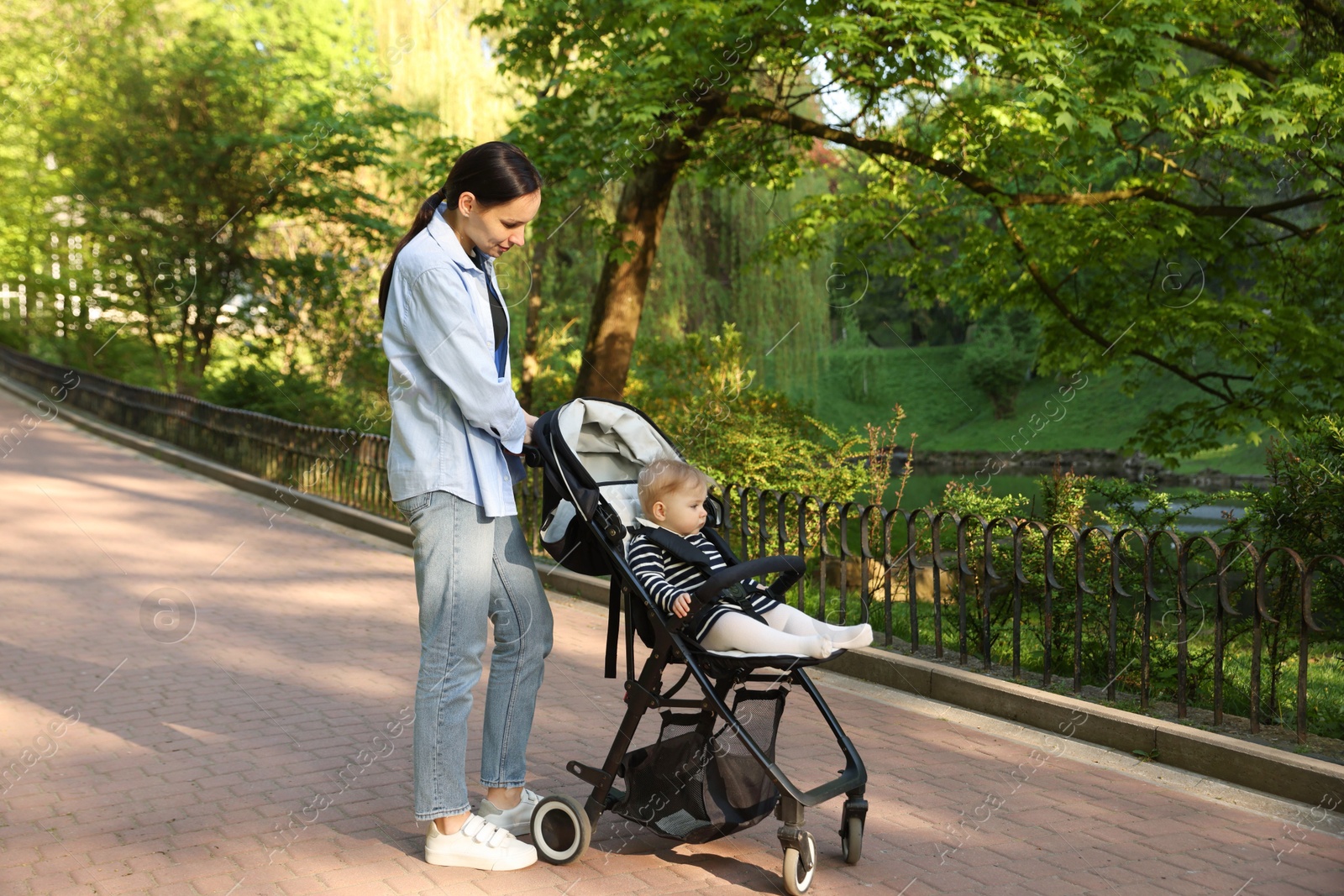 Mother walking with her baby in stroller at park. Space for text Photo of Mother walking with her baby in stroller at park. Space for text