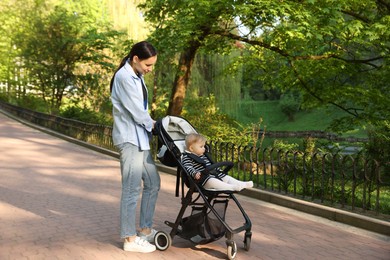 Photo of Mother walking with her baby in stroller at park. Space for text