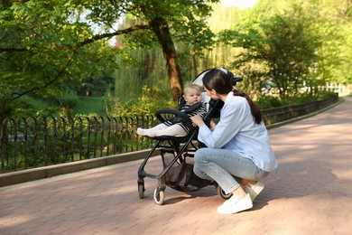 Photo of Mother with her cute baby in stroller at park. Space for text