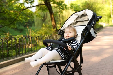 Photo of Cute little baby in stroller at park. Space for text