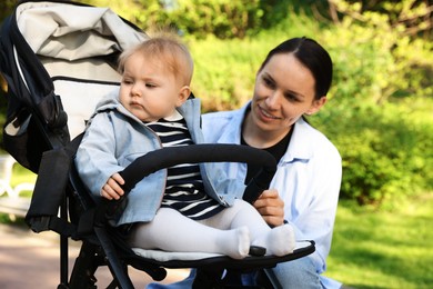 Photo of Mother with her cute baby in stroller at park