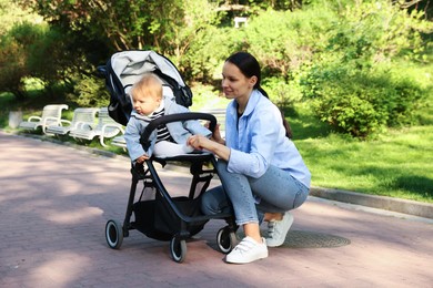 Photo of Mother with her cute baby in stroller at park