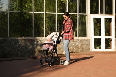 Photo of Mother walking with her baby in stroller at park