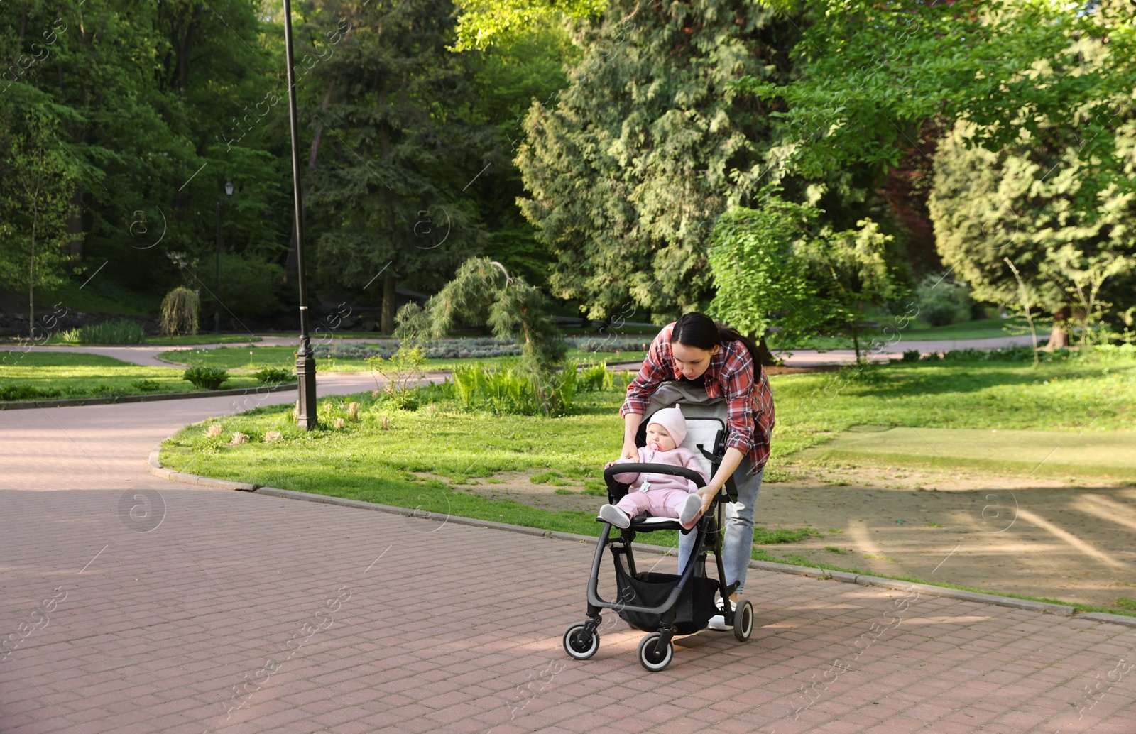 Photo of Mother walking with her baby in stroller at park. Space for text