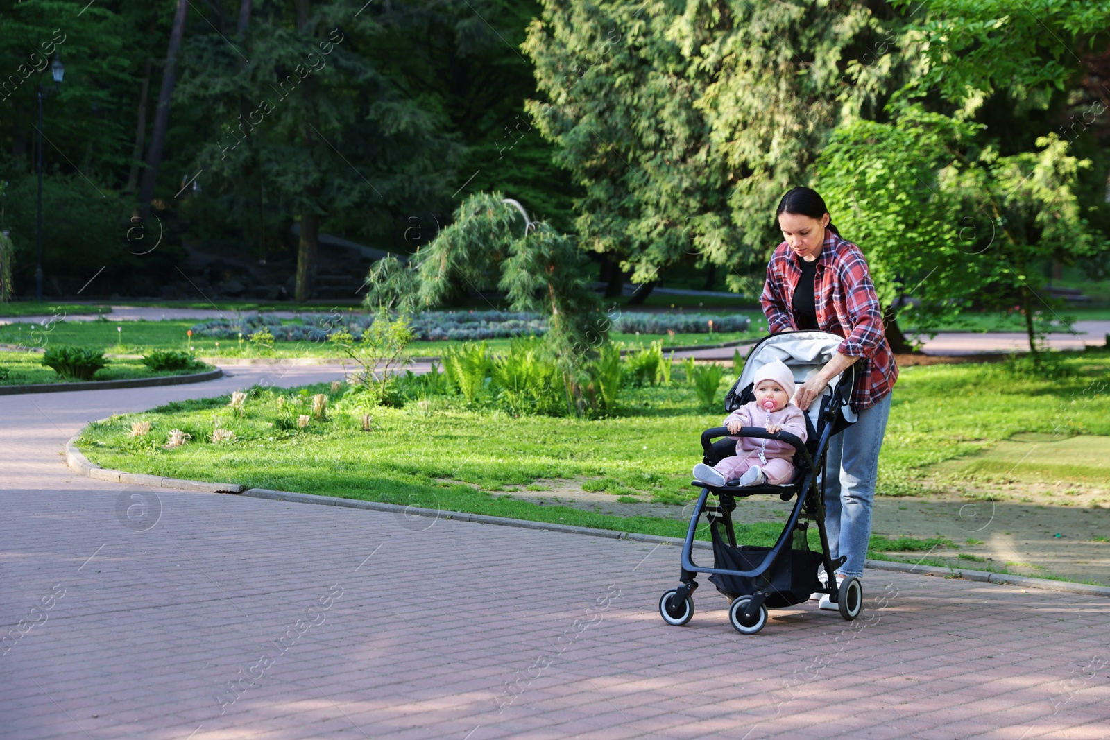 Photo of Mother walking with her baby in stroller at park. Space for text