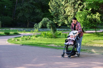 Photo of Mother walking with her baby in stroller at park. Space for text