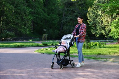 Photo of Mother walking with her baby in stroller at park. Space for text
