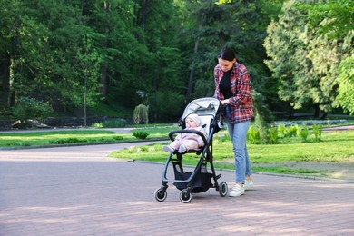Photo of Mother walking with her baby in stroller at park. Space for text