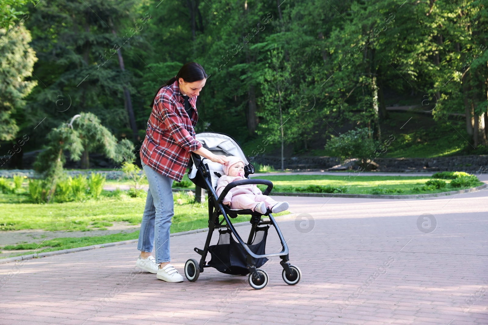 Photo of Mother walking with her baby in stroller at park. Space for text