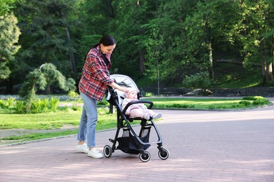 Photo of Mother walking with her baby in stroller at park. Space for text