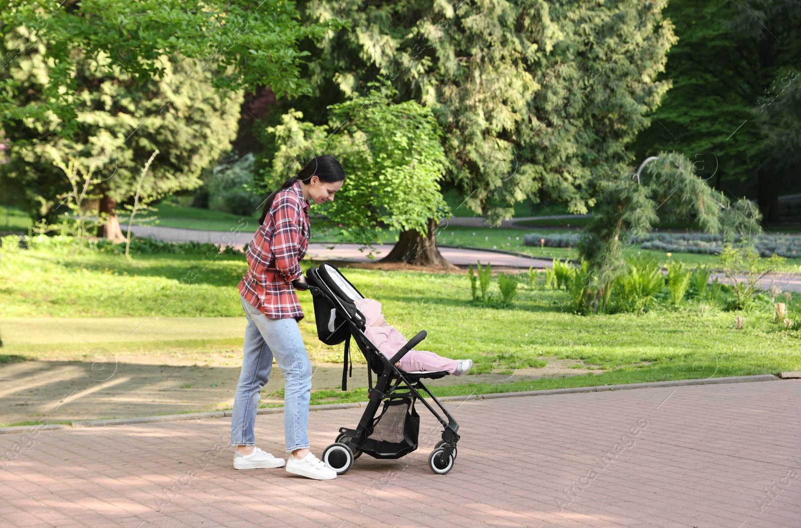Photo of Mother walking with her baby in stroller at park. Space for text