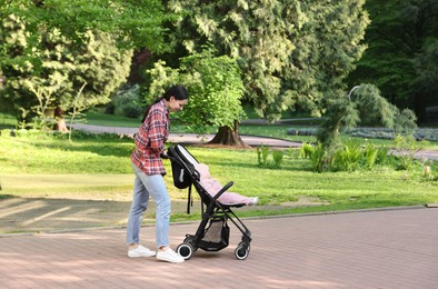 Photo of Mother walking with her baby in stroller at park. Space for text