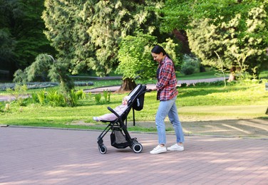 Photo of Mother walking with her baby in stroller at park