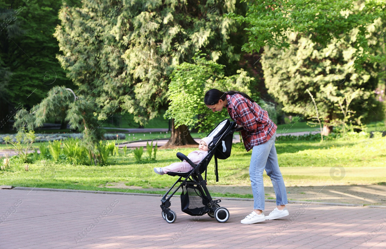 Photo of Mother walking with her baby in stroller at park. Space for text