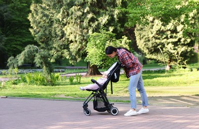 Photo of Mother walking with her baby in stroller at park. Space for text