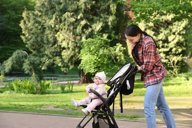 Photo of Mother walking with her baby in stroller at park. Space for text