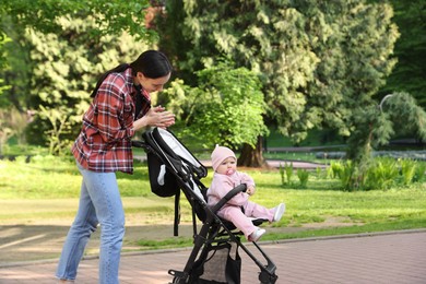 Photo of Mother walking with her baby in stroller at park. Space for text