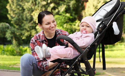 Photo of Mother with her cute baby in stroller at park