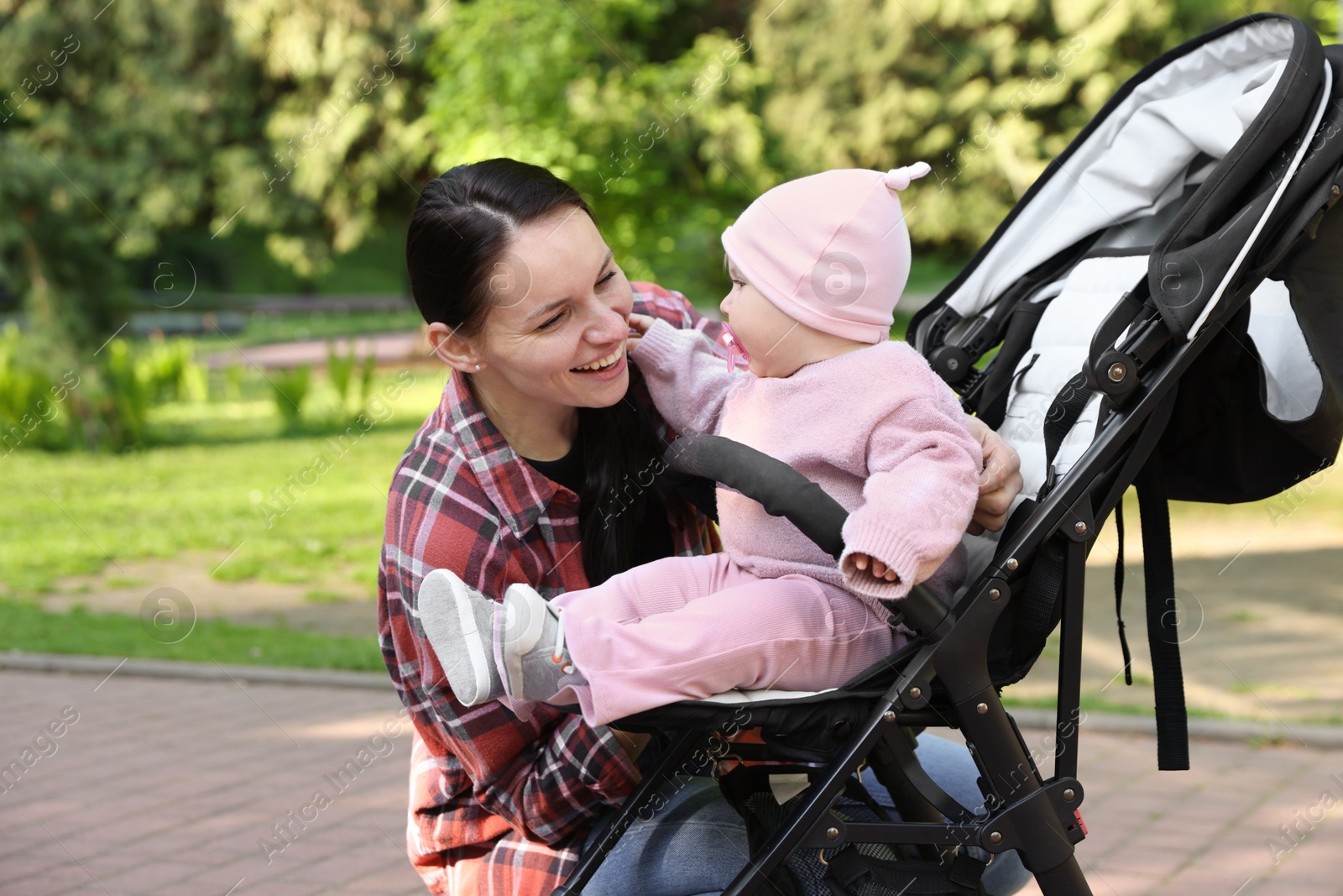 Mother with her cute baby in stroller at park Photo of Mother with her cute baby in stroller at park