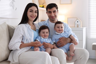 Photo of Happy family. Parents with their twin babies on sofa at home