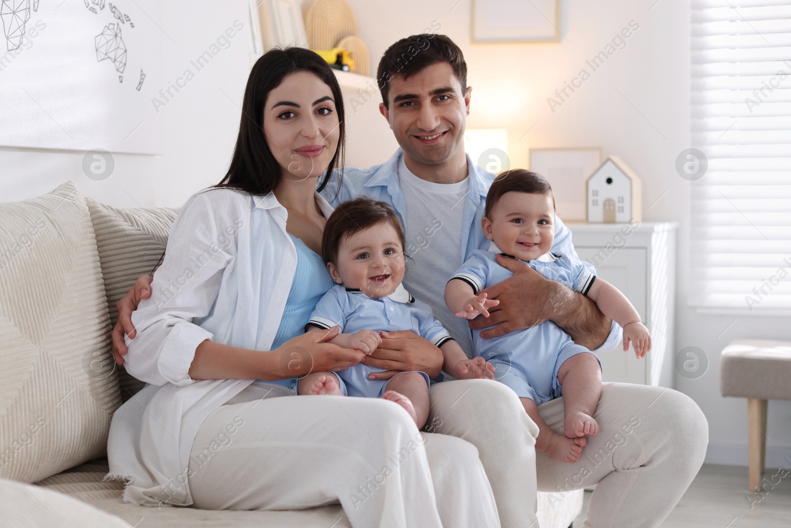 Happy family. Parents with their twin babies on sofa at home Photo of Happy family. Parents with their twin babies on sofa at home