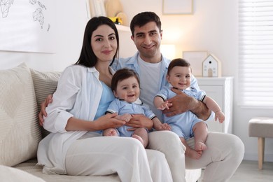 Photo of Happy family. Parents with their twin babies on sofa at home