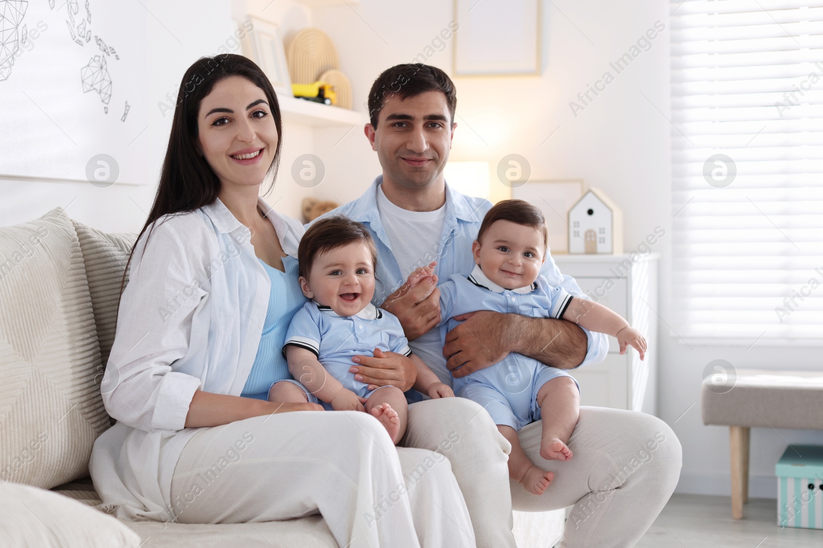 Happy family. Parents with their twin babies on sofa at home Photo of Happy family. Parents with their twin babies on sofa at home