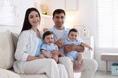 Photo of Happy family. Parents with their twin babies on sofa at home