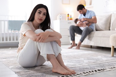 Photo of Woman suffering from postpartum depression and her husband with baby at home, selective focus