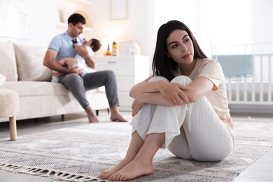 Photo of Woman suffering from postpartum depression and her husband with baby at home, selective focus