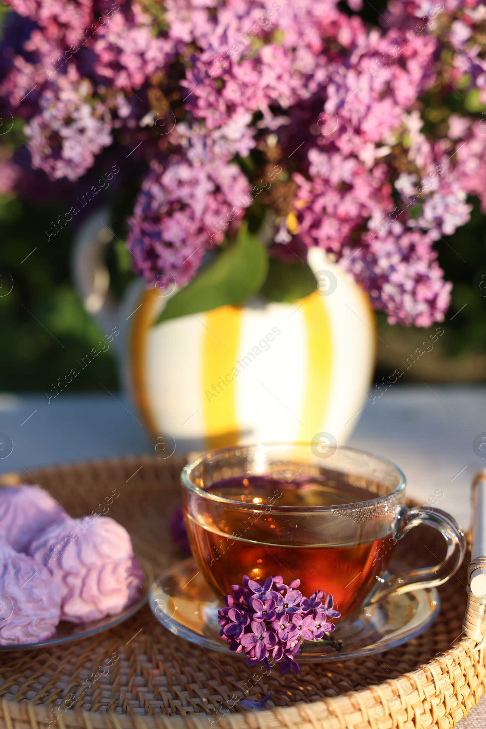 Beautiful lilac flowers, tea and zephyrs on table in garden, closeup Photo of Beautiful lilac flowers, tea and zephyrs on table in garden, closeup