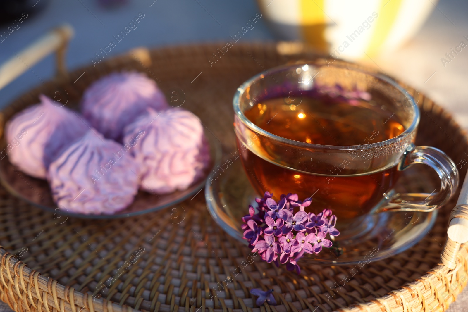 Beautiful lilac flowers, tea and zephyrs on table in garden, closeup Photo of Beautiful lilac flowers, tea and zephyrs on table in garden, closeup