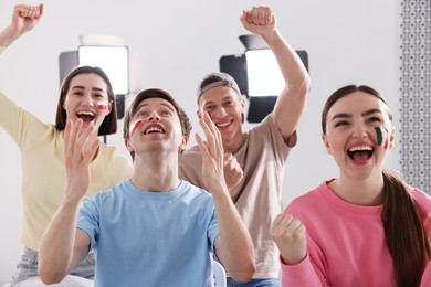 Photo of Emotional sports fans watching game together indoors, selective focus