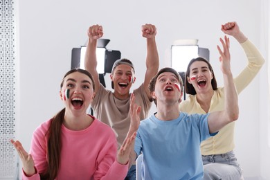 Photo of Emotional sports fans watching game together indoors