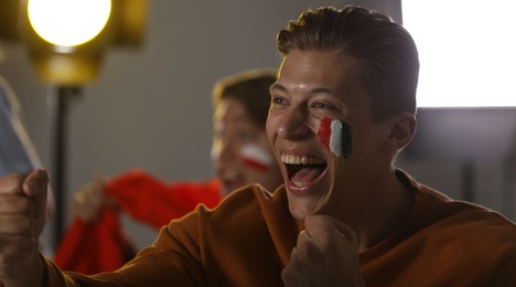 Photo of Emotional sports fans watching game together indoors