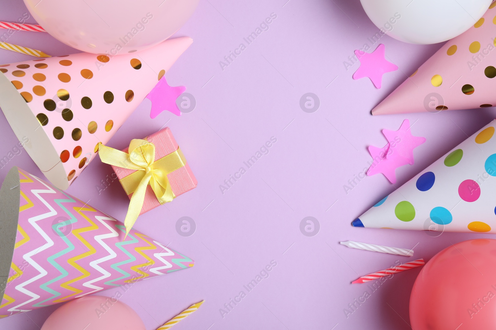 Beautiful party hats and other festive decor on lilac background, flat lay. Space for text Photo of Beautiful party hats and other festive decor on lilac background, flat lay. Space for text