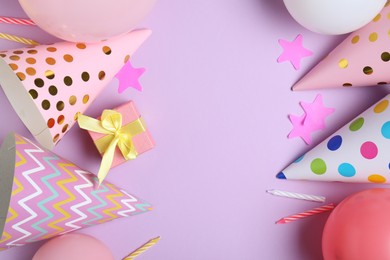 Photo of Beautiful party hats and other festive decor on lilac background, flat lay. Space for text