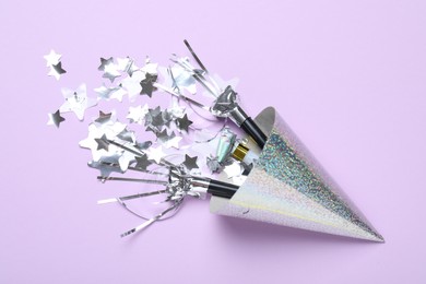 Photo of Beautiful party hat, confetti and blowers on lilac background, flat lay