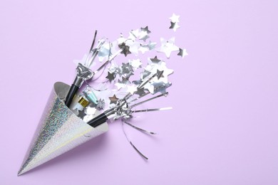Photo of Beautiful party hat, confetti and blowers on lilac background, flat lay. Space for text