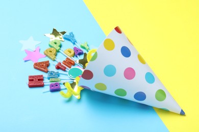 Photo of Beautiful party hat, topper and confetti on color background