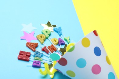 Photo of Beautiful party hat, topper and confetti on color background, closeup