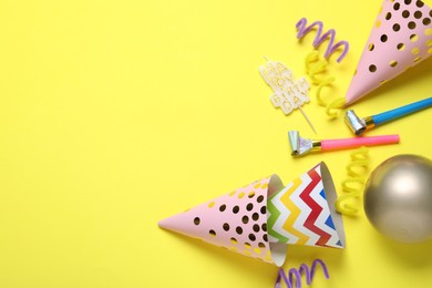 Photo of Beautiful party hats and other festive decor on yellow background, flat lay. Space for text