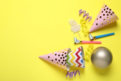 Photo of Beautiful party hats and other festive decor on yellow background, flat lay. Space for text