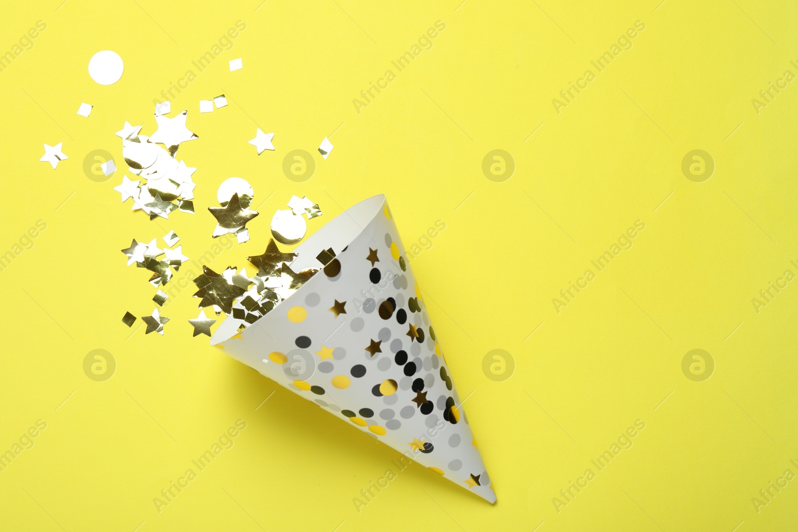 Beautiful party hat and confetti on yellow background, flat lay. Space for text Photo of Beautiful party hat and confetti on yellow background, flat lay. Space for text