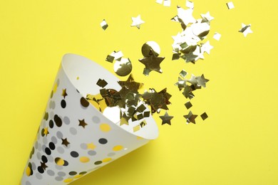 Photo of Beautiful party hat and confetti on yellow background, flat lay