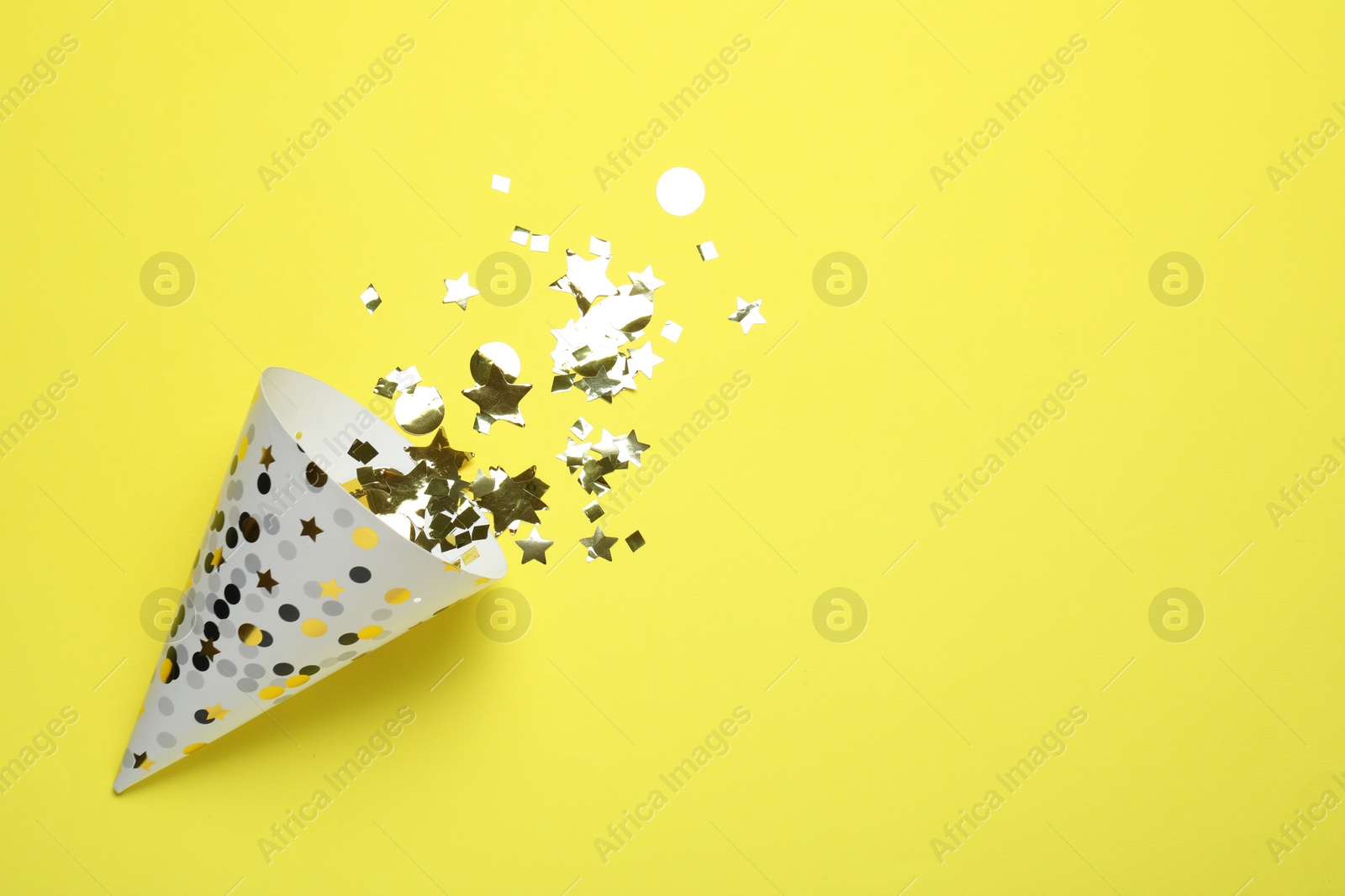 Beautiful party hat and confetti on yellow background, flat lay. Space for text Photo of Beautiful party hat and confetti on yellow background, flat lay. Space for text