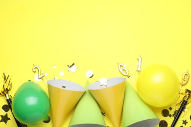 Photo of Beautiful party hats and other festive decor on yellow background, flat lay. Space for text