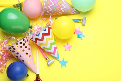 Photo of Beautiful party hats and other festive decor on yellow background, flat lay. Space for text