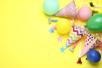 Photo of Beautiful party hats and other festive decor on yellow background, flat lay. Space for text
