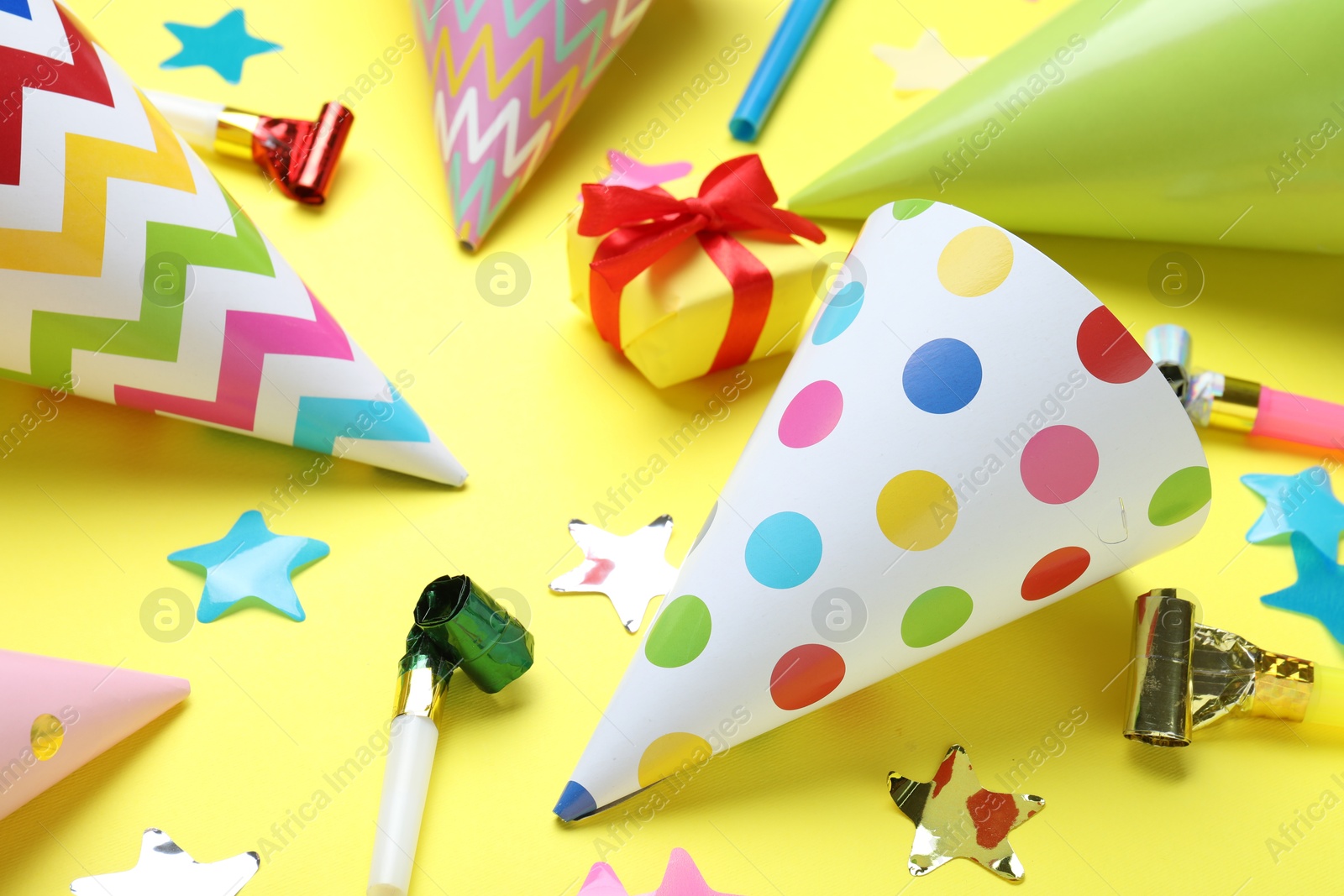 Beautiful party hats and other festive decor on yellow background, closeup Photo of Beautiful party hats and other festive decor on yellow background, closeup